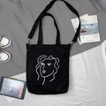 Détail du sac cabas en toile noire avec visage minimaliste et bandoulière amovible - Déesse Élégante Noir (Double Usage)