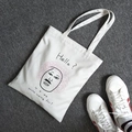 Dettaglio di una borsa tote in tela bianca con illustrazione artistica e scritta stampata - Stile Afro Cambio Colore