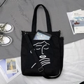 Détail du sac cabas en toile noire montrant l'espace pour tablette et le motif artistique - Visage Timide Noir (Double Usage)