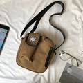 Detail of tan canvas crossbody bag with a checkered fashion label on white fabric - Khaki