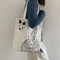 Detail view of large canvas tote bag with rabbit print and panda plush pendant on model - Rabbit Print (With Panda Charm) / White