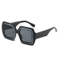 Occhiali da sole squadrati oversize neri con accenti grigio-blu su sfondo bianco puro - Montatura Nera Lenti Grigio Nero