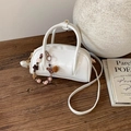 Detail of white leather barrel handbag with beaded heart charm on a wooden table - With Charm / Off White