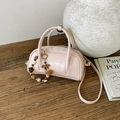 Detailed close-up of a pink mini Boston bag with floral charm on a rustic wooden desk - With Charm / Pink