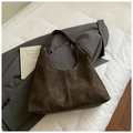 Detail einer dunkelbraunen Wildleder-Hobotasche mit weißen Kontrastnähten auf grauem Blazer - Kaffee ohne Anhänger