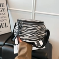 Fashionable zebra print saddle bag with black woven strap and silver hardware accents - Black