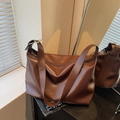 Brown leather tote bag with wide strap and golden hardware in minimalist aesthetic - Brown