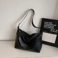 Primer plano del bolso hobo de cuero negro mate con hebilla dorada y cremallera de metal - Negro