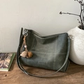 Detail of dark green suede tote with white contrast stitching and tassel on wooden table - Green with Pendant