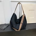 Detail view of black canvas tote bag with brown leather handles and silver studs - Black