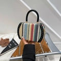 Rainbow woven bucket bag with black circular handle and gold chain strap in hand - Iridescent Black