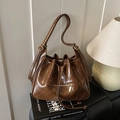 Vintage brown quilted bucket bag with drawstring and adjustable strap on black books - Brown