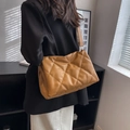 Gesteppte Tragetasche aus braunem Kunstleder mit breitem Riemen in Innenraum-Setting - Khaki