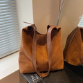 Brown vintage suede bucket bag with adjustable strap on a dark wood background - Brown