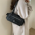 Schwarze Vintage-Motorradtasche mit silbernen Schnallen auf einem beigen Mantel - Schwarz