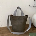 Detailansicht der Vintage Wildleder Beuteltasche mit gewebtem Riemen auf Holztisch - Grün
