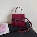 Detail of burgundy suede handbag featuring decorative wrap-around belt buckle and strap - Red