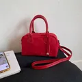 Red suede handbag with round top handles and a silver heart pendant accessory - Red