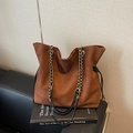 Braune Wildleder-Beuteltasche mit Kettenriemen und Kordelzug auf einem Ledersofa - Braun Groß