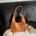 Bohemian caramel suede hobo bag with long tassels and adjustable strap in a cozy setting - Yellow Brown