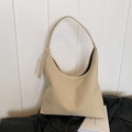 Bolso hobo beige de cuero suave sobre un fondo elegante de chaqueta negra - Blanco Roto