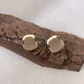 Dettaglio ravvicinato di orecchini quadrati con finitura opaca dorata su corteccia - Quadrato Smerigliato Oro (Stile Principale)