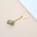 Detail view of a natural conch shell keychain with polished gold edges and a gold keyring - 14# (Green Textured Conch)