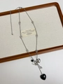 Detail of silver long necklace with black heart bead and metallic pendant on tray - Silver Long Chain Black Heart