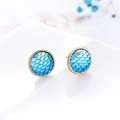 Vista macro di orecchini a lobo con scaglie di pesce blu su supporto riflettente - K5 / Celeste