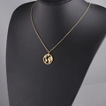 Detail einer goldenen Weltkarten-Halskette auf einer schwarzen Büste mit feiner O-Kette - Gold