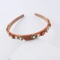 Macro shot of orange satin headband with vintage crystals and pearls on white stone - Orange