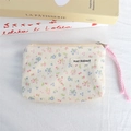 Close-up of floral corduroy coin purse with zipper and pink wrist strap on books - Cream Base Small Floral