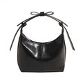 Detail of a black glossy leather crescent bag featuring a stylish bow on the handle strap - Black