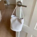 Sac seau blanc à texture tressée avec bandoulière suspendu à une poignée de porte - Blanc