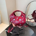 Sac à main chic en cuir rouge avec rivets et nœud décoratif porté par la main - Rouge