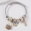 Pulsera plateada con colgante de gato, estrella y dijes grabados sobre un fondo blanco - café