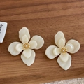 Detailed macro view of cream layered flower earrings with gold center and tiny rhinestone - Off White