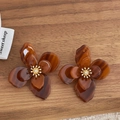 Vue détaillée des boucles d'oreilles fleurs en acrylique ambre avec étamines dorées - Ambre Foncé