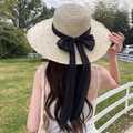 Women's beige wide brim straw sun hat with long black ribbon bow in an outdoor setting - Large Streamer Ribbon Beige Black