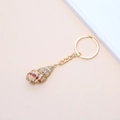 Golden keychain featuring a natural spiral seashell with dark brown textures on pink backdrop - 15# (Partially Gilded Conch)