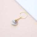Golden keychain with natural pearl-finish conch shell pendant on warm pink background - 48# (Pearl Luster Spiral Conch)