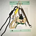 Cartoon plush bear keychain with green hat, brown spring coil and black braided cord - Spring Rope Pendant / White Puppy