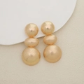 Détail de boucles d'oreilles dorées à trois niveaux avec texture en métal brossé mat - Or Mat