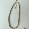 Détail du collier de perles artisanal avec pierres bleu clair et perles d'espacement dorées - Collier / Motif Serpent