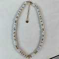 Détail macro de perles de marbre blanc et d'entretoises dorées sur un collier perlé - Collier / Jade Blanc