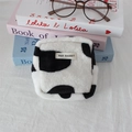 Flat lay of a plush cow print square organizer bag with a May Rabbit woven label - Large Cow Print
