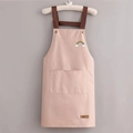 Pink waterproof apron with rainbow embroidery and dark brown straps hanging on a hanger - Rainbow Pink (Standard Style)