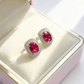 Close-up of elegant oval red ruby stud earrings with halo diamonds in a luxury jewelry box - Red Heart Stud Earrings