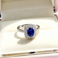 Macro view of oval royal blue sapphire ring with double halo diamond setting in white gold - Blue Ring