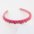 Detailed close-up of rose pink satin headband with hand-set pink rhinestones on white stand - Champagne Pear Shape Gem (Style F)